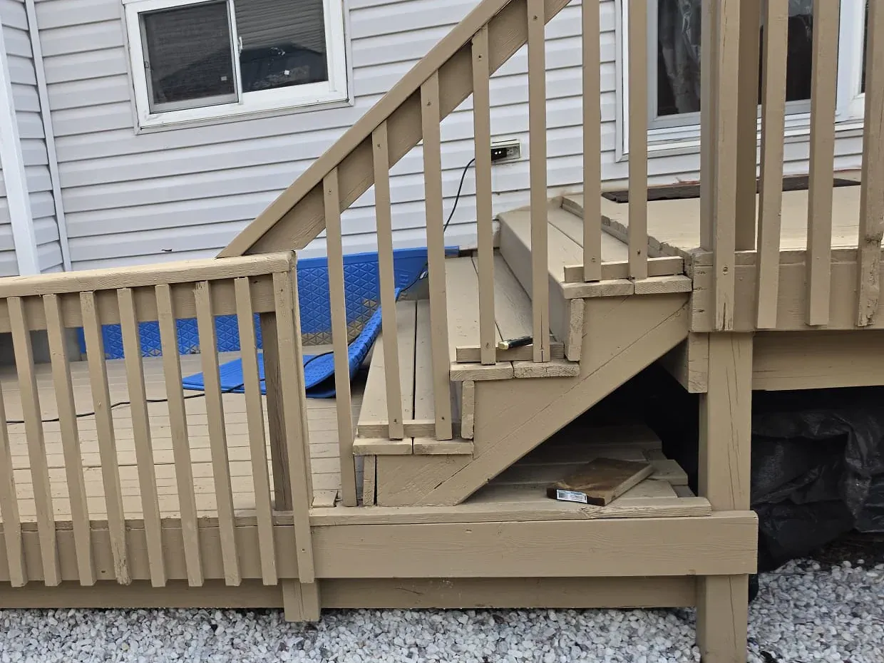 Stained wood deck with a railing and stairs at the back of a two-storey home