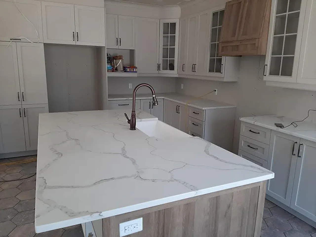 Kitchen with white shaker cabinets, a marble-look quartz waterfall island, and a bronze gooseneck faucet