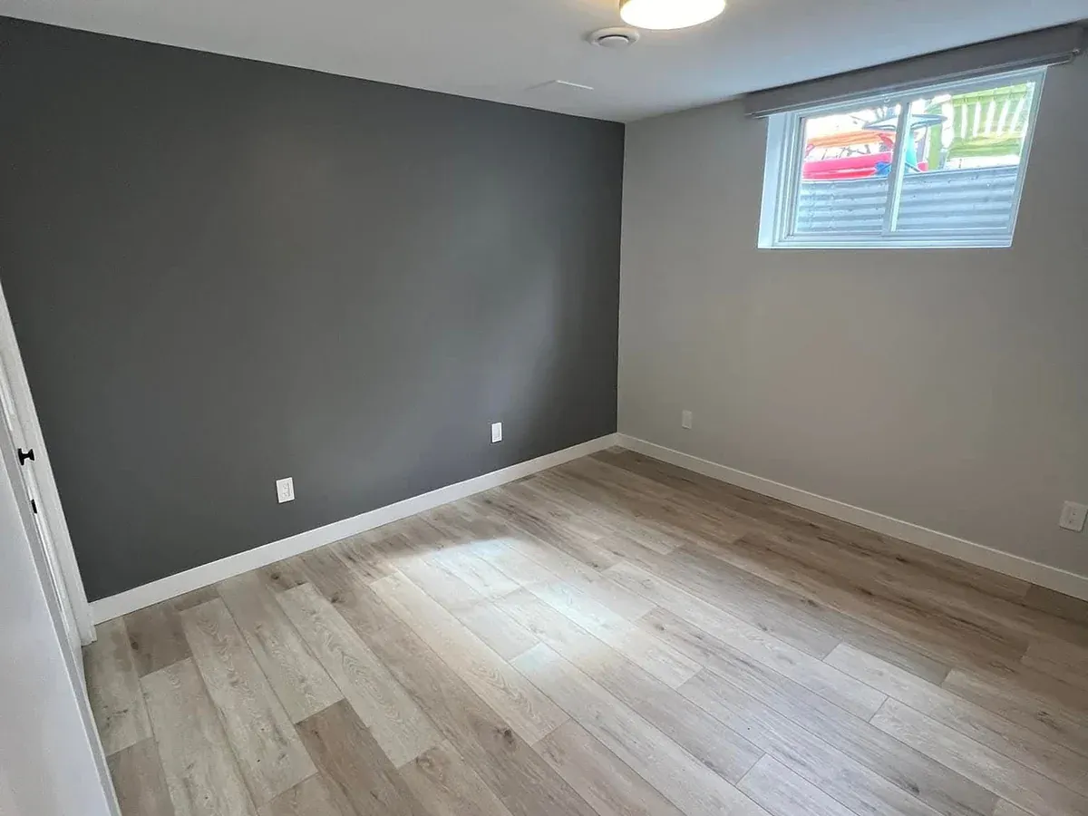 Freshly painted room in charcoal grey with a white ceiling, white trim, and light plank flooring